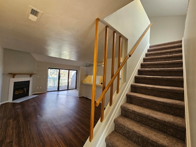 staircase featuring a fireplace and hardwood / wood-style flooring