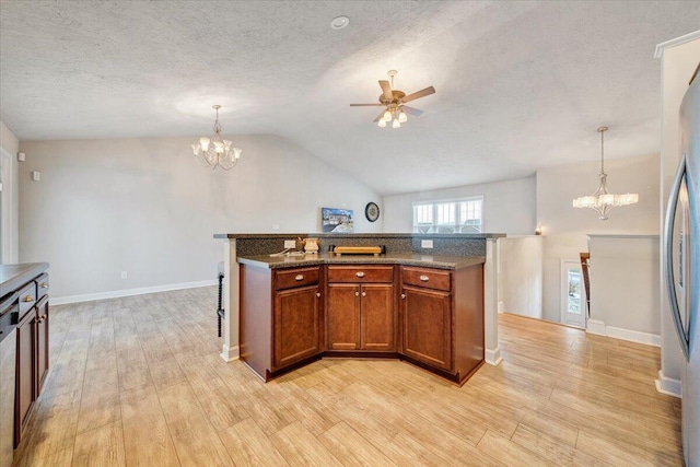 kitchen with a kitchen island with sink, pendant lighting, vaulted ceiling, and ceiling fan with notable chandelier