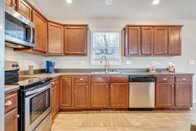 kitchen with appliances with stainless steel finishes, light hardwood / wood-style flooring, and sink