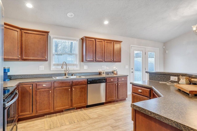 kitchen featuring stainless steel appliances, sink, a textured ceiling, an inviting chandelier, and light hardwood / wood-style flooring