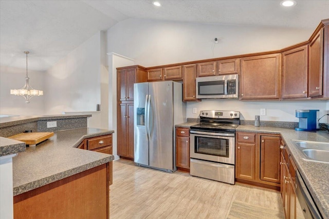 kitchen featuring sink, decorative light fixtures, vaulted ceiling, a chandelier, and appliances with stainless steel finishes