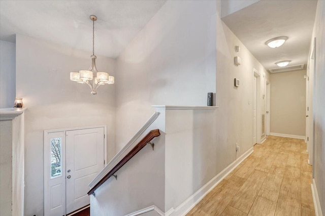 foyer featuring light wood-type flooring and an inviting chandelier