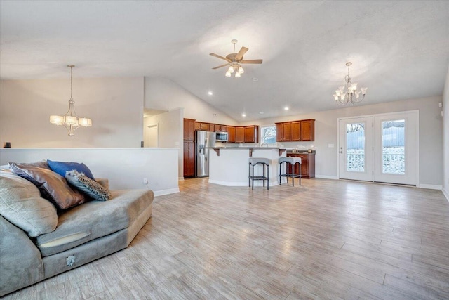 living room featuring light hardwood / wood-style floors, vaulted ceiling, and ceiling fan with notable chandelier