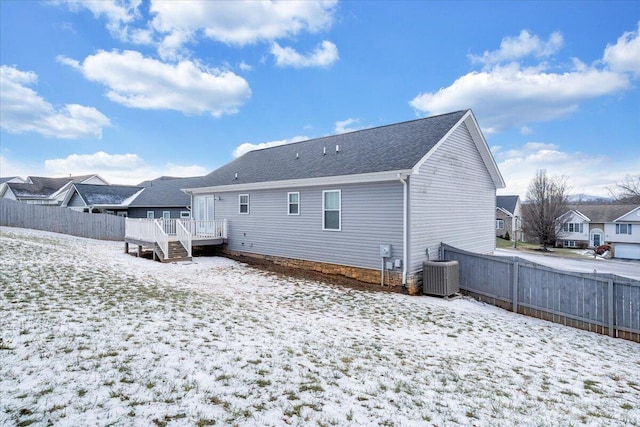 snow covered rear of property with central air condition unit and a wooden deck