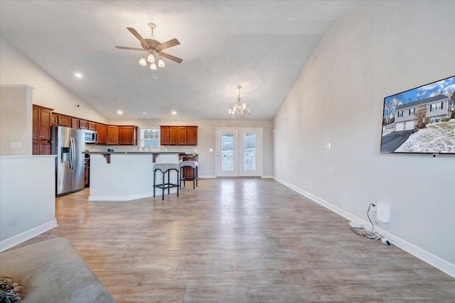 kitchen featuring pendant lighting, stainless steel appliances, a kitchen island, a breakfast bar area, and ceiling fan with notable chandelier