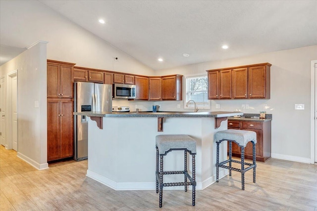 kitchen featuring stainless steel appliances, a kitchen bar, a center island, and light wood-type flooring