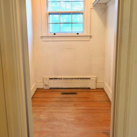 laundry area with baseboard heating and light hardwood / wood-style flooring