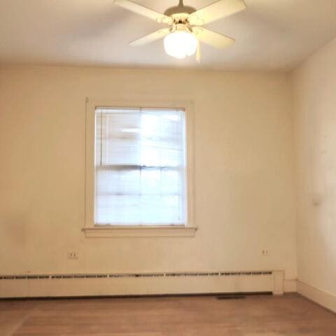 empty room with hardwood / wood-style floors, a baseboard heating unit, and ceiling fan