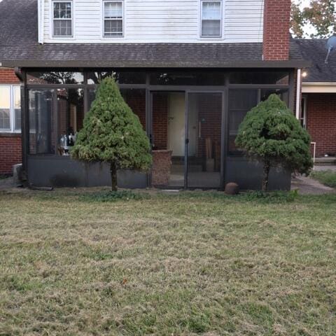 rear view of house with a yard and a sunroom