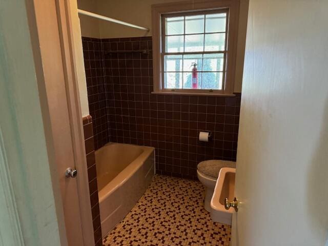 bathroom with tiled shower / bath, tile walls, toilet, and tile patterned flooring