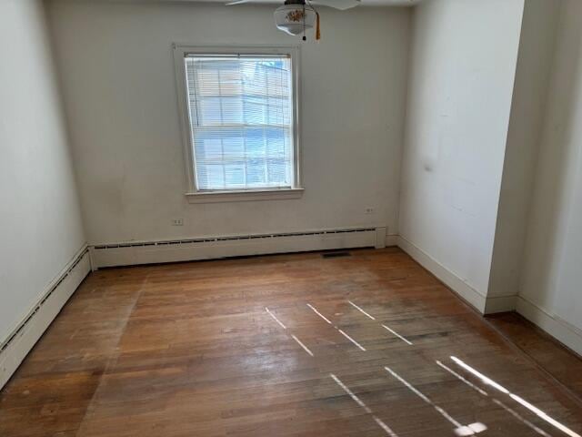 spare room featuring ceiling fan, baseboard heating, and dark hardwood / wood-style floors