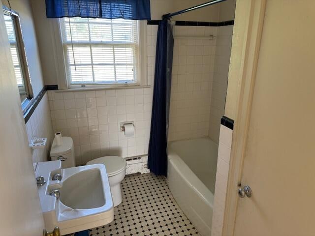 full bathroom with shower / tub combo, tile walls, toilet, sink, and tile patterned flooring