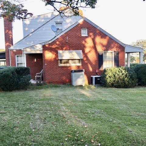 back of house featuring central AC and a yard