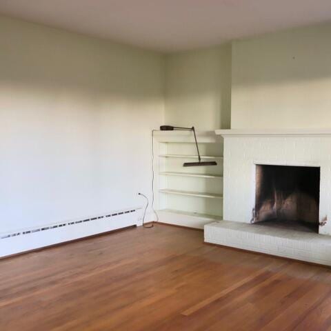 unfurnished living room featuring dark hardwood / wood-style flooring, a fireplace, and a baseboard heating unit