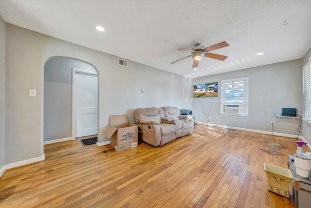 living room featuring ceiling fan, cooling unit, a textured ceiling, and light wood-type flooring