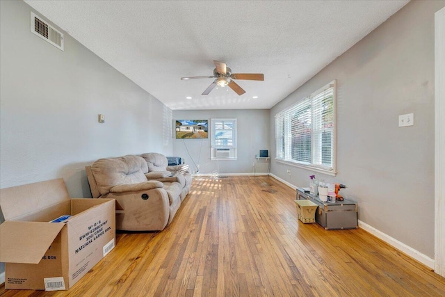 living room featuring a textured ceiling, light hardwood / wood-style floors, and ceiling fan