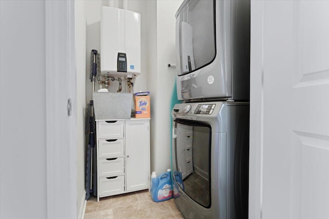 laundry area with light tile patterned floors, tankless water heater, and stacked washer and clothes dryer