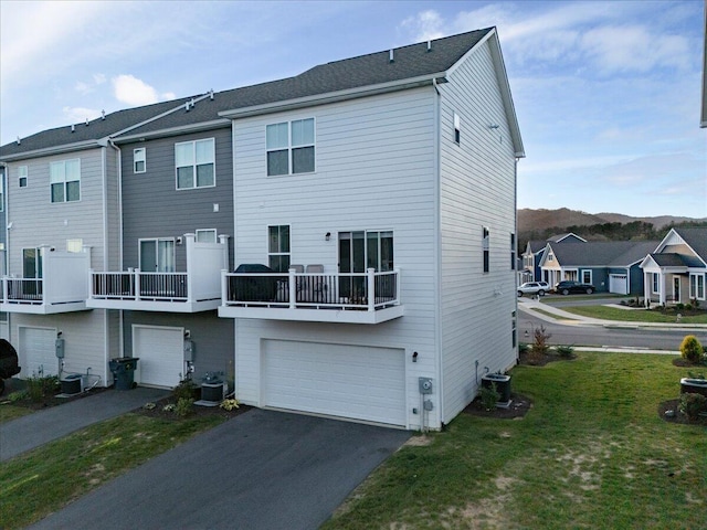 rear view of house with central AC unit, a garage, and a balcony