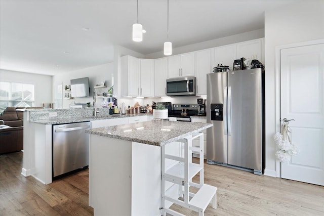 kitchen featuring appliances with stainless steel finishes, a kitchen breakfast bar, white cabinetry, light wood-type flooring, and pendant lighting