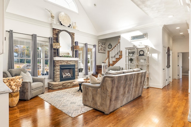 living room featuring ornamental molding, high vaulted ceiling, wood-type flooring, and a fireplace