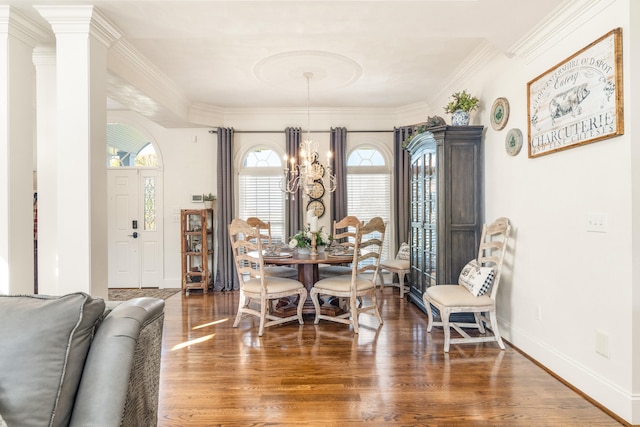 dining area featuring crown molding, decorative columns, an inviting chandelier, and dark hardwood / wood-style floors