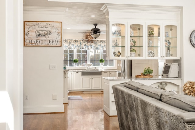 bar with ceiling fan, white cabinetry, light stone countertops, light hardwood / wood-style flooring, and crown molding