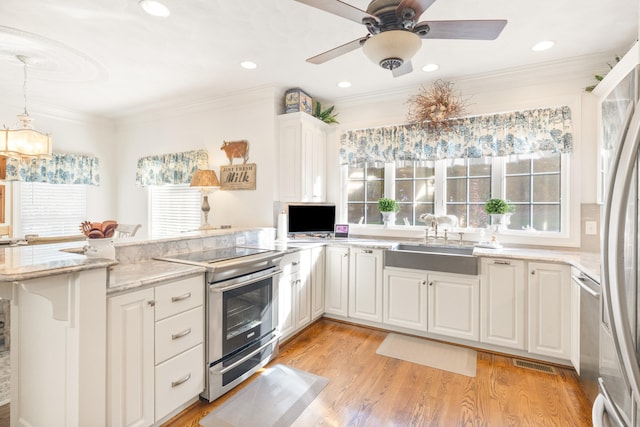 kitchen with sink, light wood-type flooring, stainless steel appliances, white cabinets, and ornamental molding