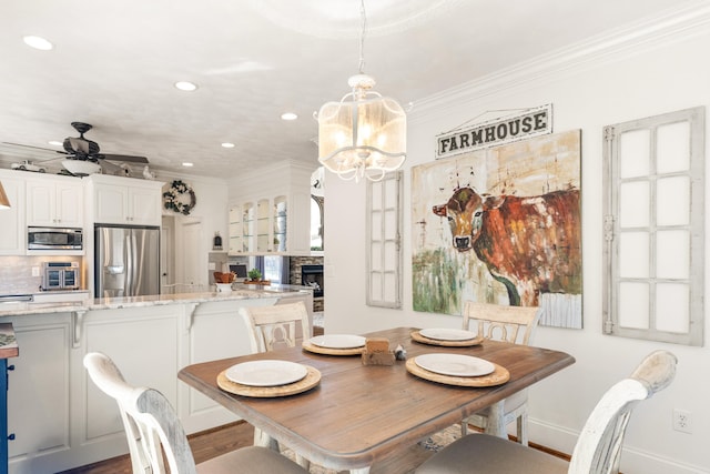 dining room with ornamental molding, hardwood / wood-style floors, and ceiling fan with notable chandelier