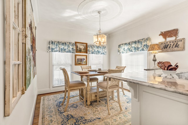 dining space with a notable chandelier, crown molding, a healthy amount of sunlight, and light wood-type flooring