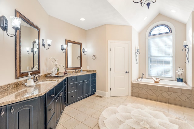 bathroom with vanity, tile patterned flooring, tiled tub, and vaulted ceiling