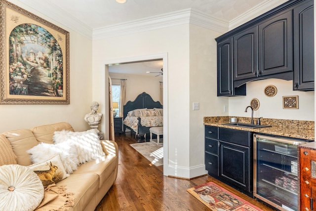 interior space featuring wine cooler, light stone counters, dark wood-type flooring, crown molding, and sink