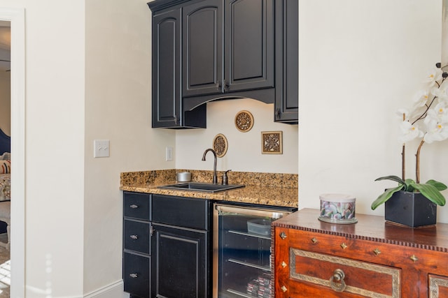 kitchen with wine cooler, sink, and dark stone counters