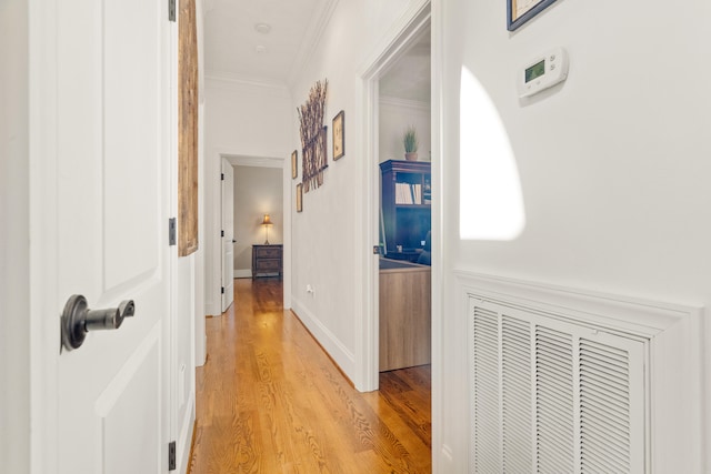 hall with ornamental molding and light wood-type flooring