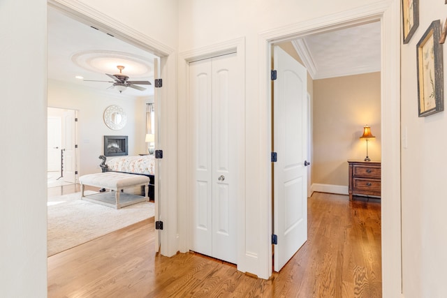 corridor with ornamental molding and hardwood / wood-style floors