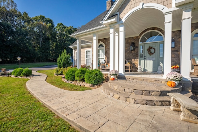 view of exterior entry with a yard and covered porch