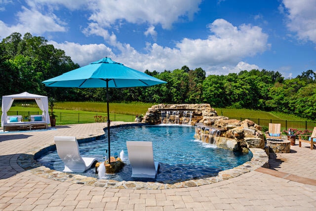 view of swimming pool featuring a patio area, pool water feature, and an outdoor fire pit