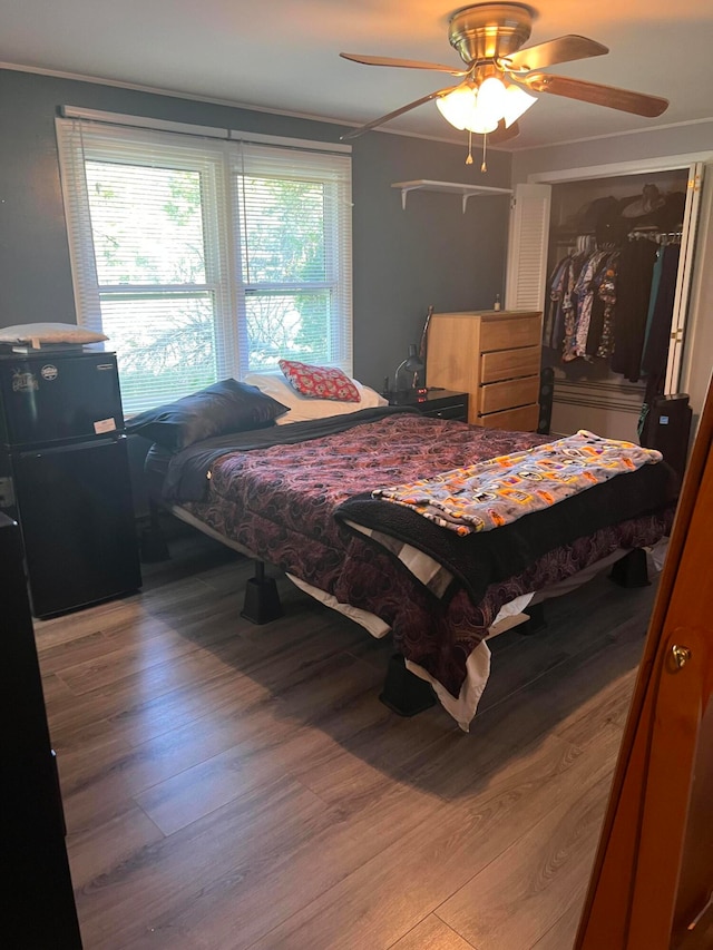 bedroom with ceiling fan, wood-type flooring, and ornamental molding