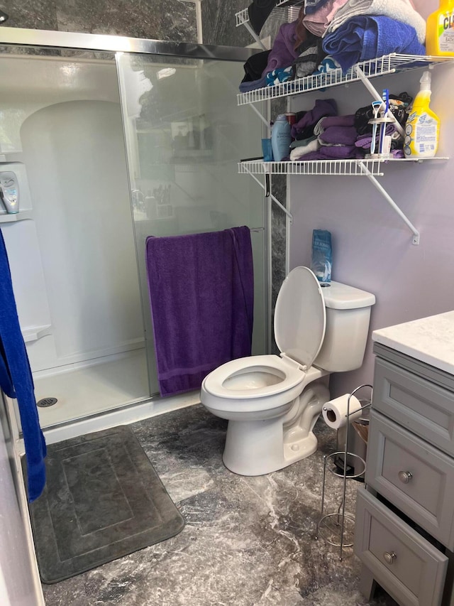 bathroom featuring a shower with door, toilet, and vanity