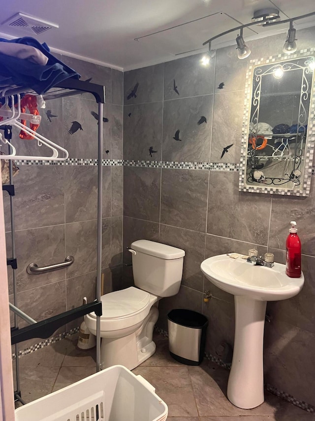 bathroom featuring toilet, tile patterned floors, and tile walls