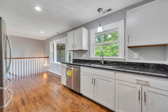 kitchen with white cabinets, stainless steel appliances, visible vents, and a sink