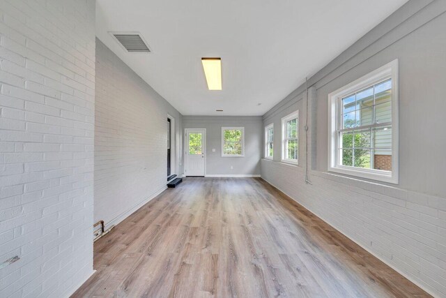 interior space featuring wood finished floors, brick wall, and visible vents