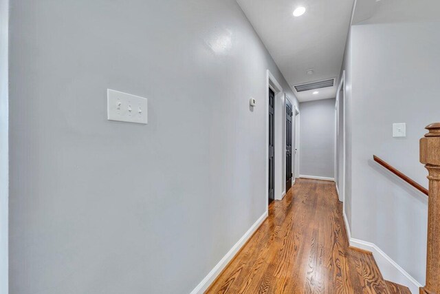 hallway with recessed lighting, baseboards, an upstairs landing, wood finished floors, and visible vents