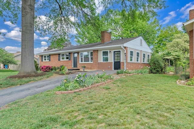 single story home featuring brick siding, driveway, a chimney, and a front lawn