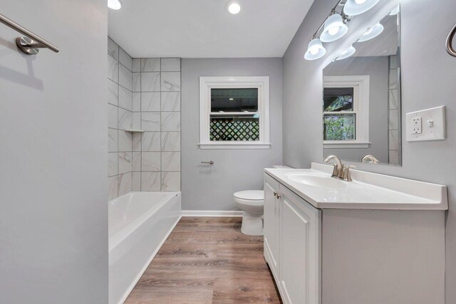 bathroom with vanity, toilet, baseboards, tub / shower combination, and wood finished floors