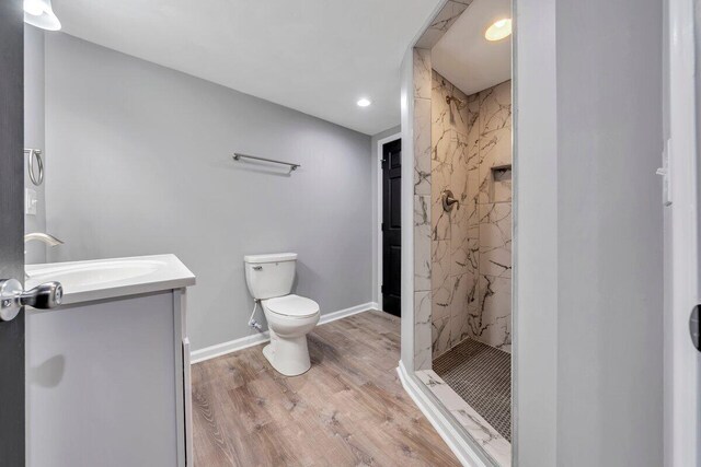 bathroom featuring vanity, toilet, a marble finish shower, recessed lighting, and wood finished floors