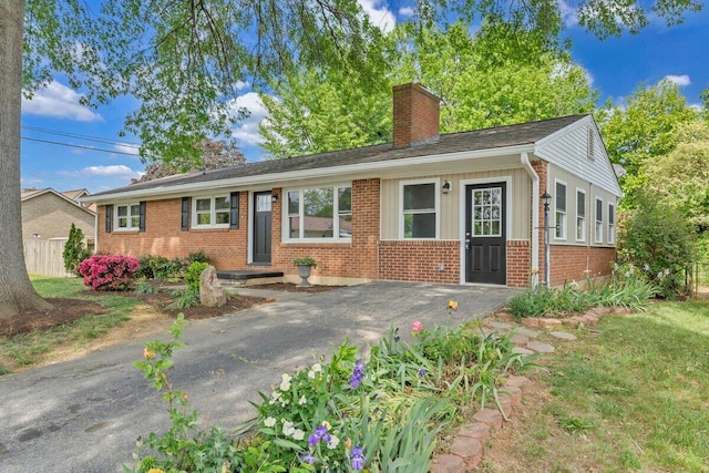 single story home featuring board and batten siding, a chimney, and brick siding