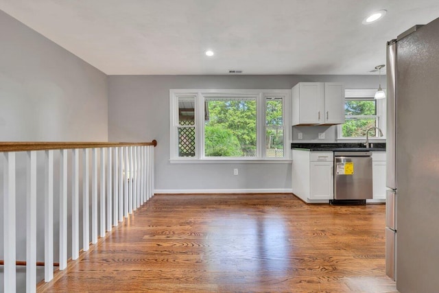 kitchen with dark countertops, appliances with stainless steel finishes, baseboards, light wood finished floors, and white cabinetry