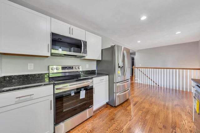 kitchen with white cabinets, dark stone countertops, light wood-style floors, stainless steel appliances, and recessed lighting