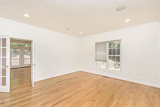 unfurnished room with ornamental molding, french doors, and light hardwood / wood-style floors