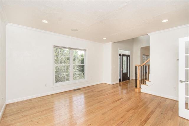 spare room with ornamental molding and light wood-type flooring